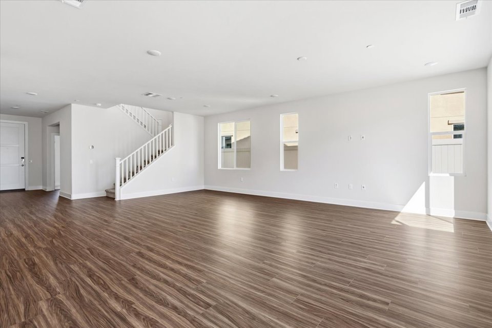 A large empty room with a wood floor and white walls.