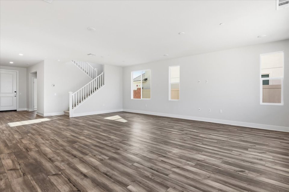 A large empty room with a wood floor and white walls.