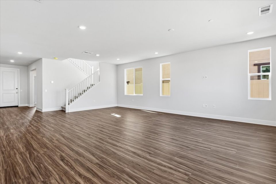 A large empty room with a wood floor and white walls.