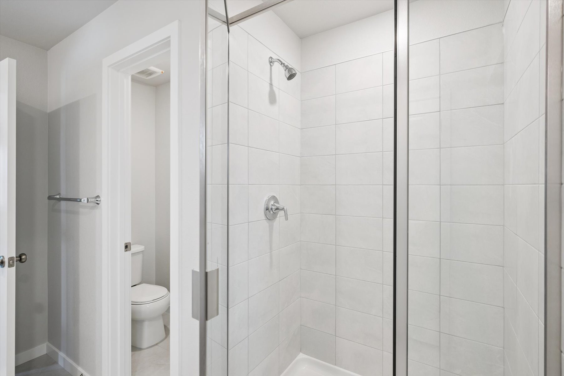 A bathroom with a shower unit and toilet.