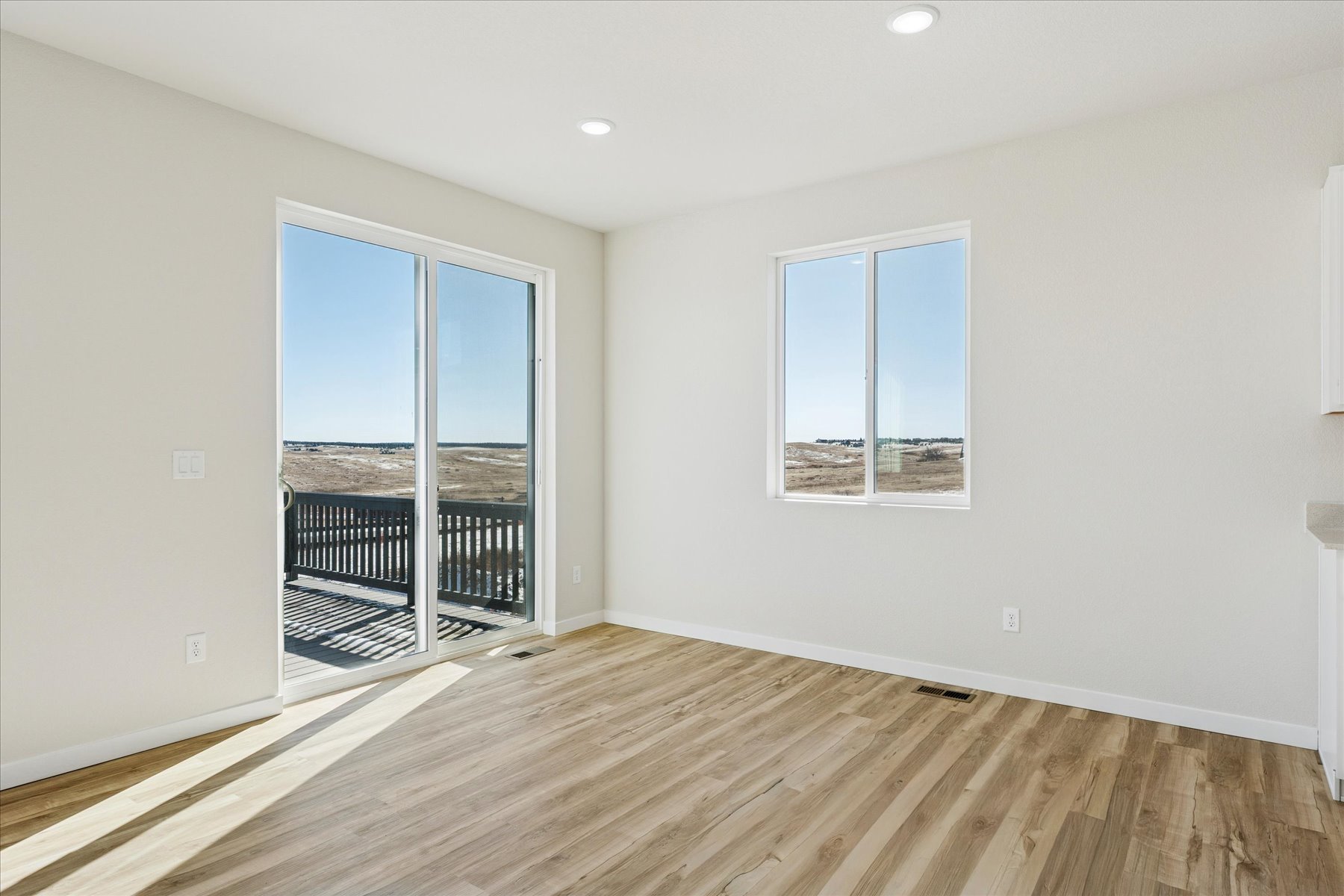A room with a wood floor and a window with a view of the water.