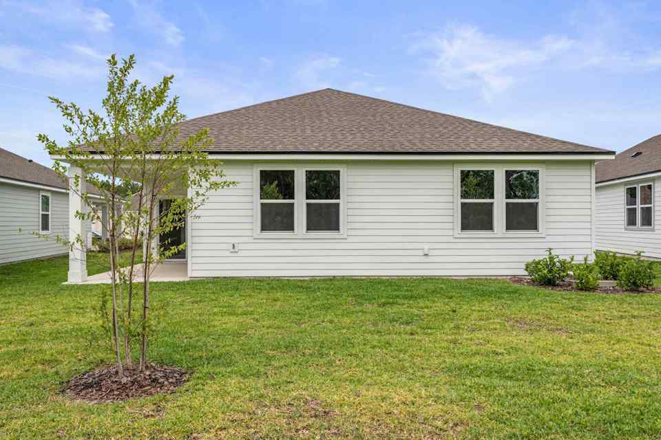 Palmetto Floorplan Lot 145 Backyard with Tree and Covered Patio at Seminole Palms in Palm Coast