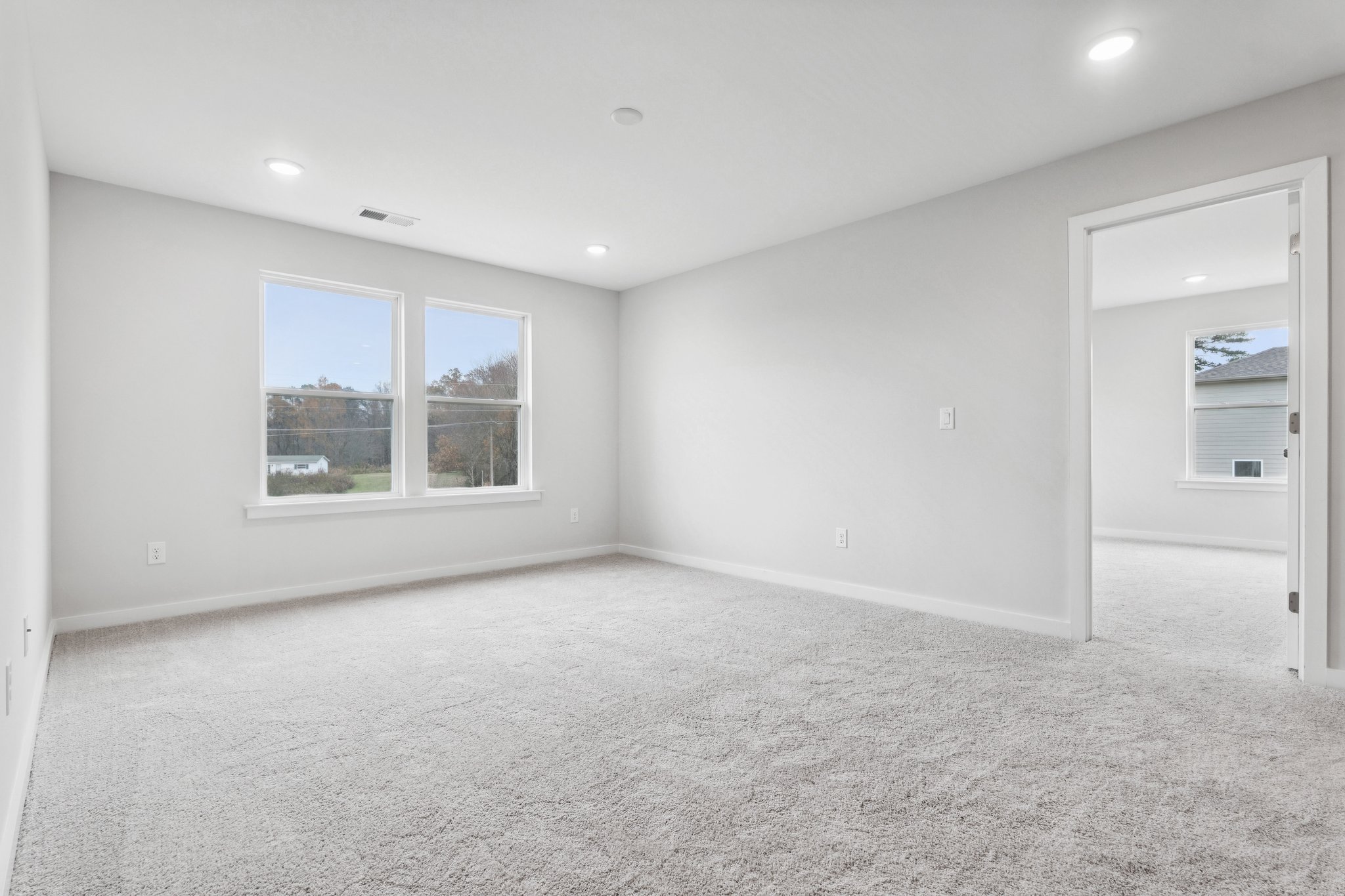 A room with a white carpet and windows.