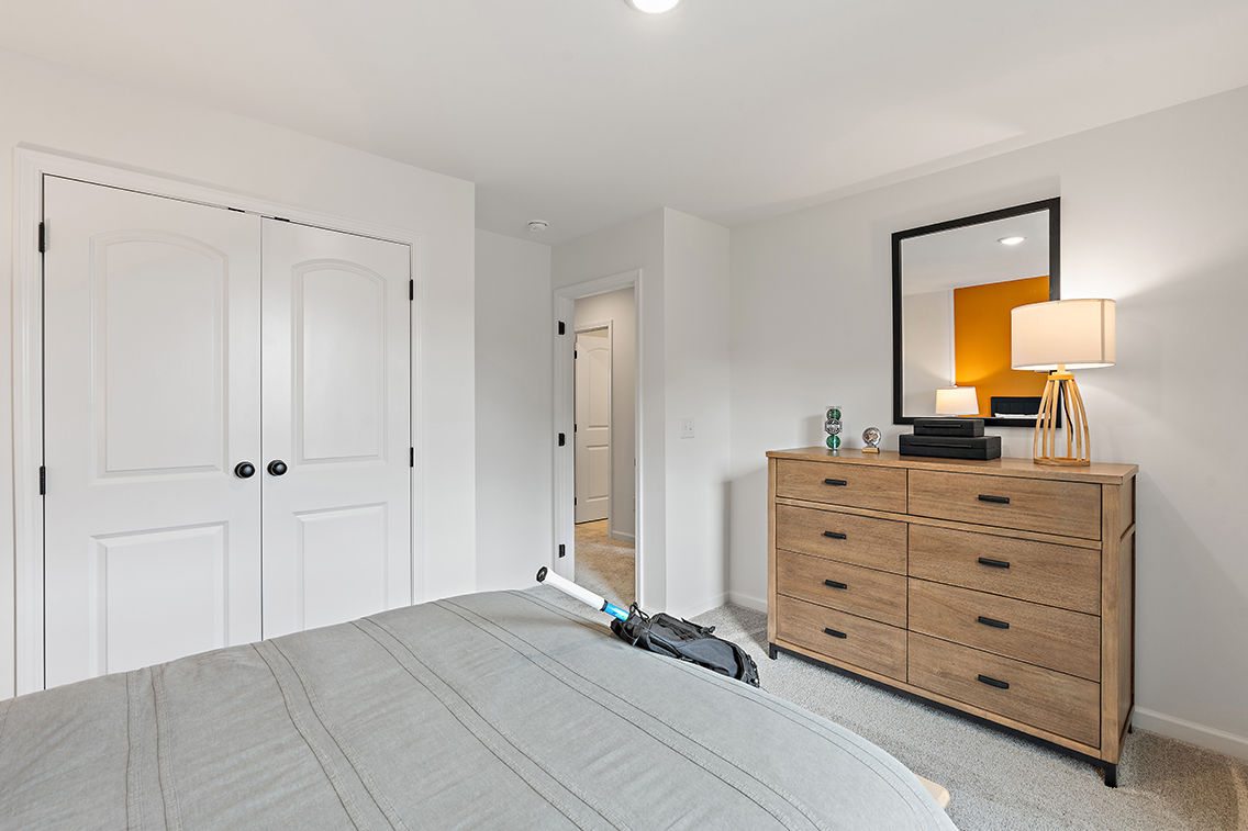 A bedroom with a bed and dresser.