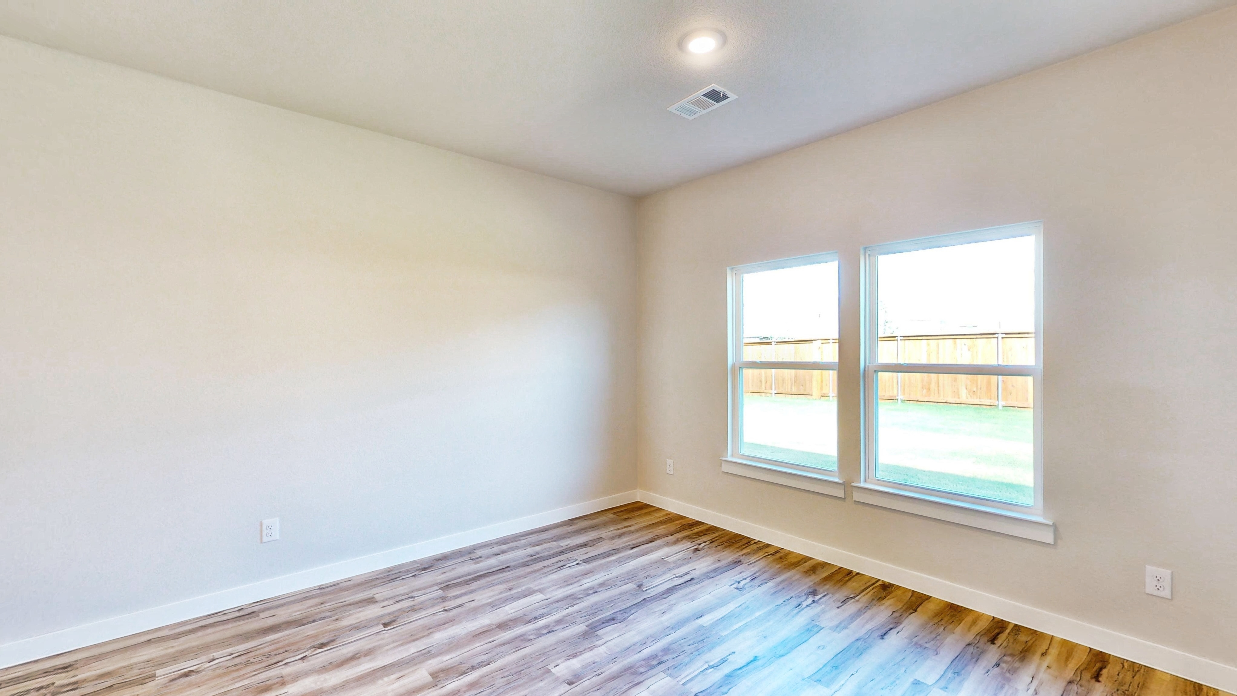 A room with a window and a wood floor.