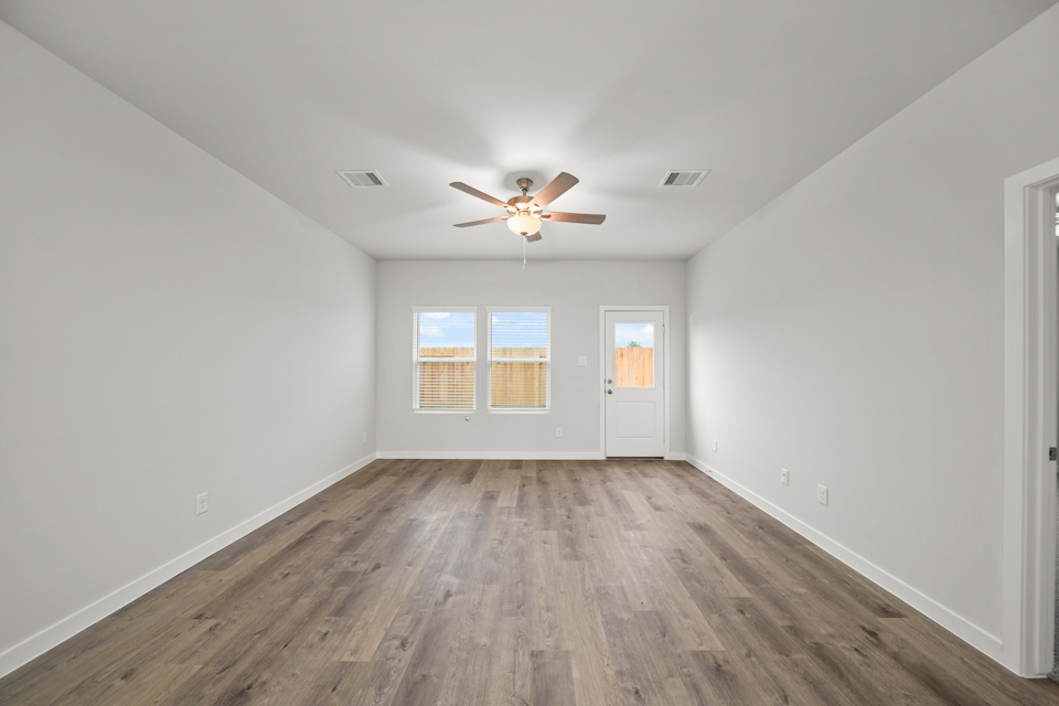 A room with a ceiling fan and a wood floor.