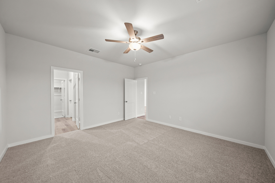 A room with a ceiling fan and a carpet.