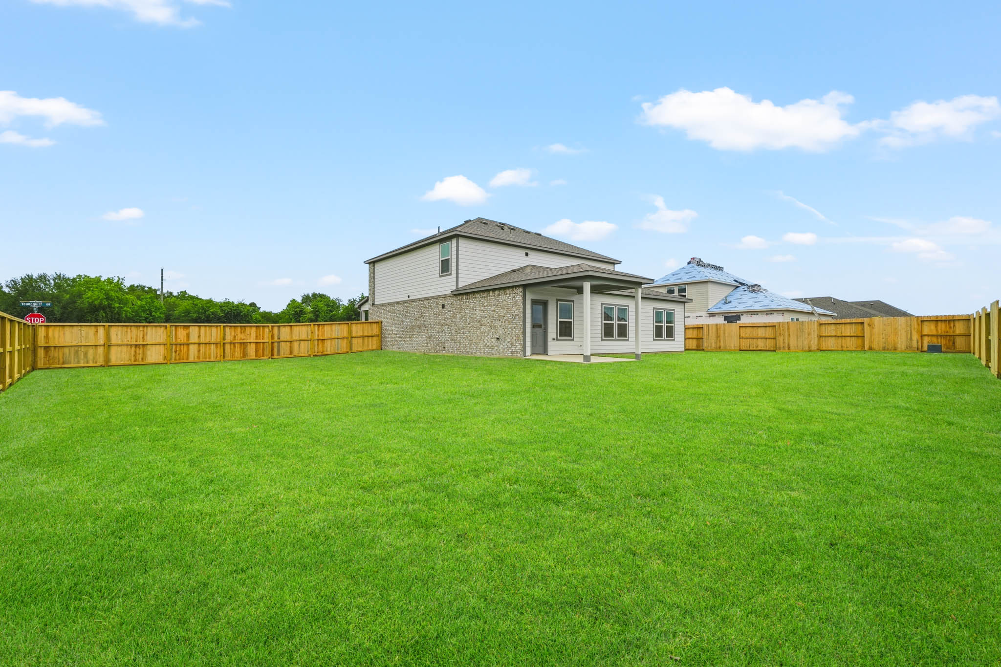 A large green field with a house in the background.