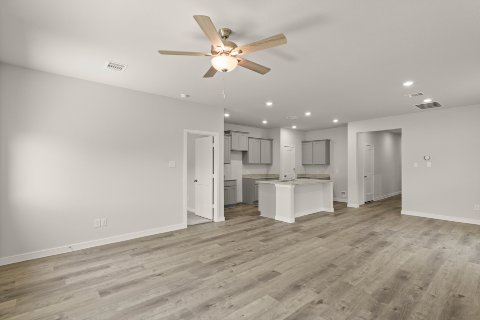 A room with a ceiling fan and a wood floor.