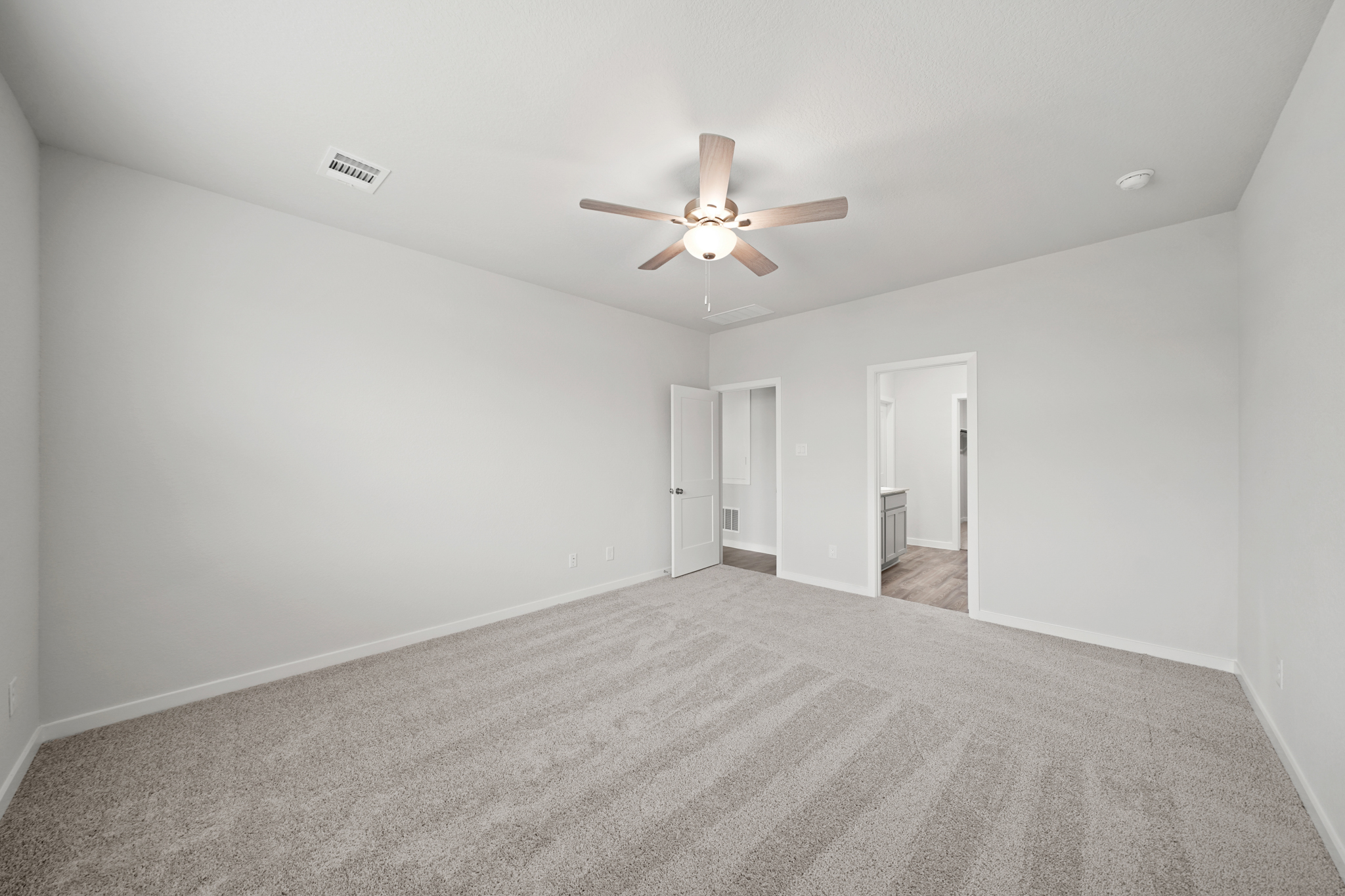 A room with a ceiling fan and carpet.