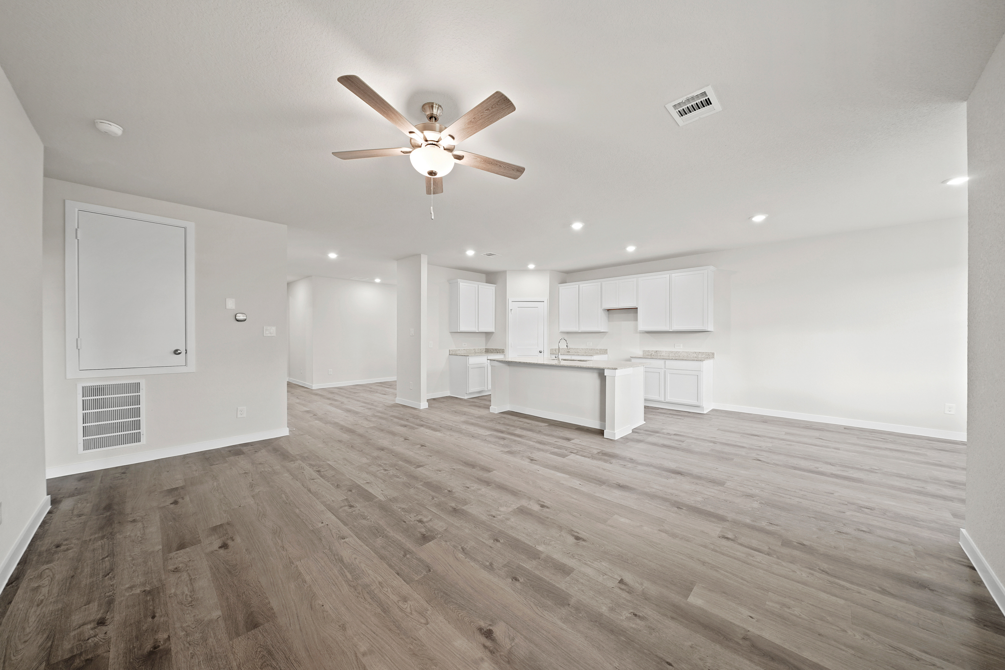 A large empty room with a ceiling fan and a wood floor.