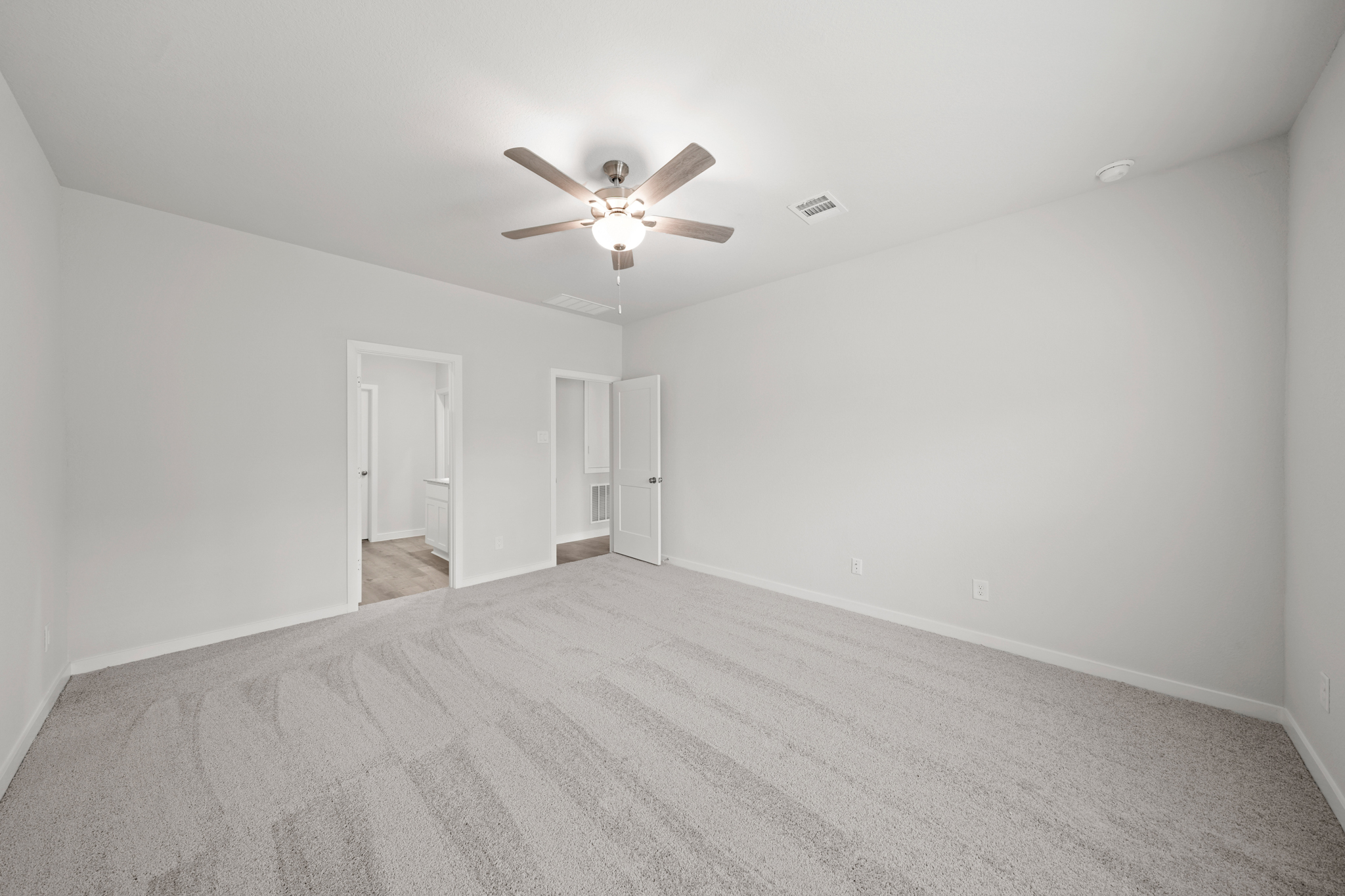 A room with a ceiling fan and a carpet.