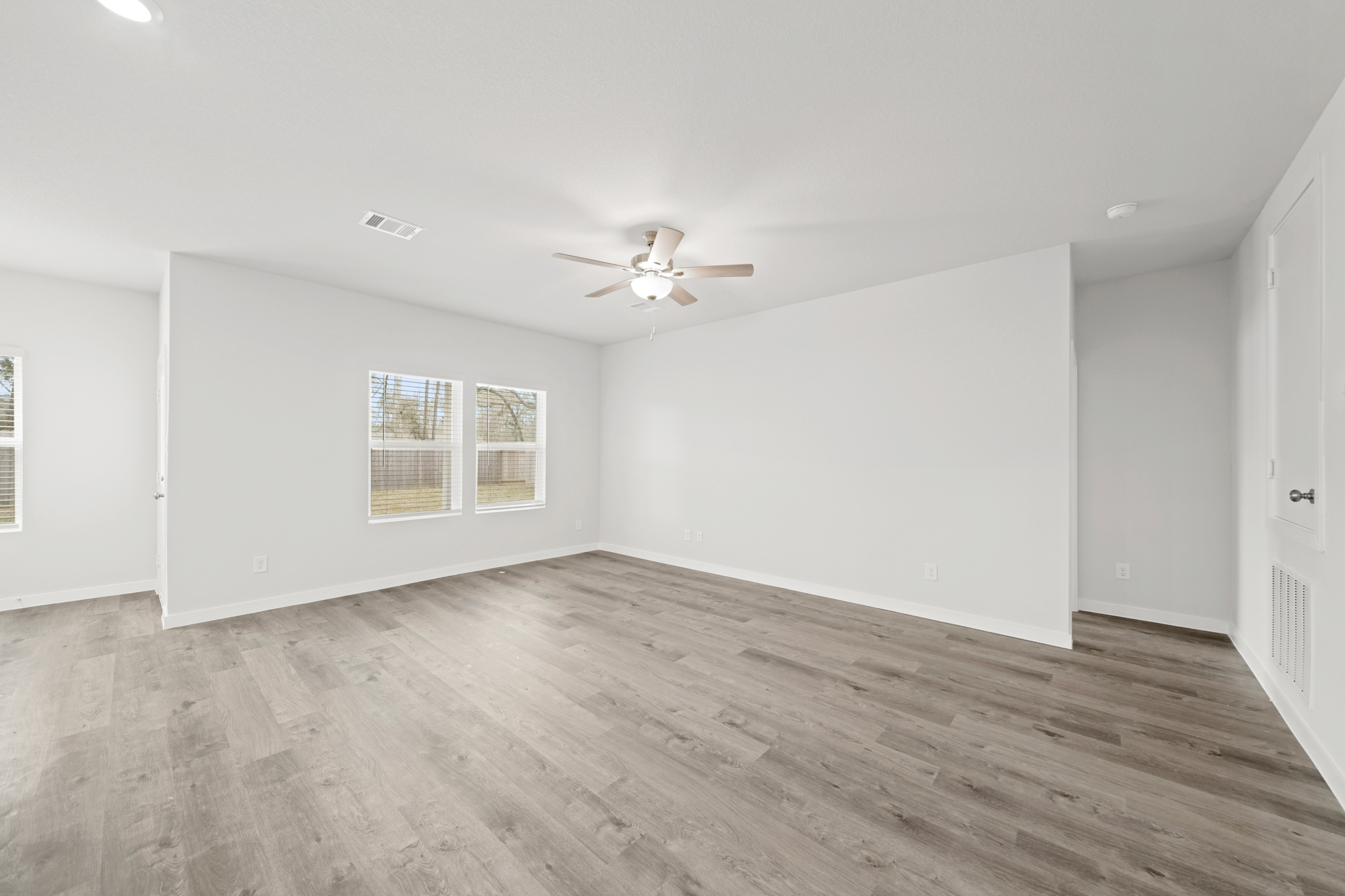A room with a wood floor and a ceiling fan.