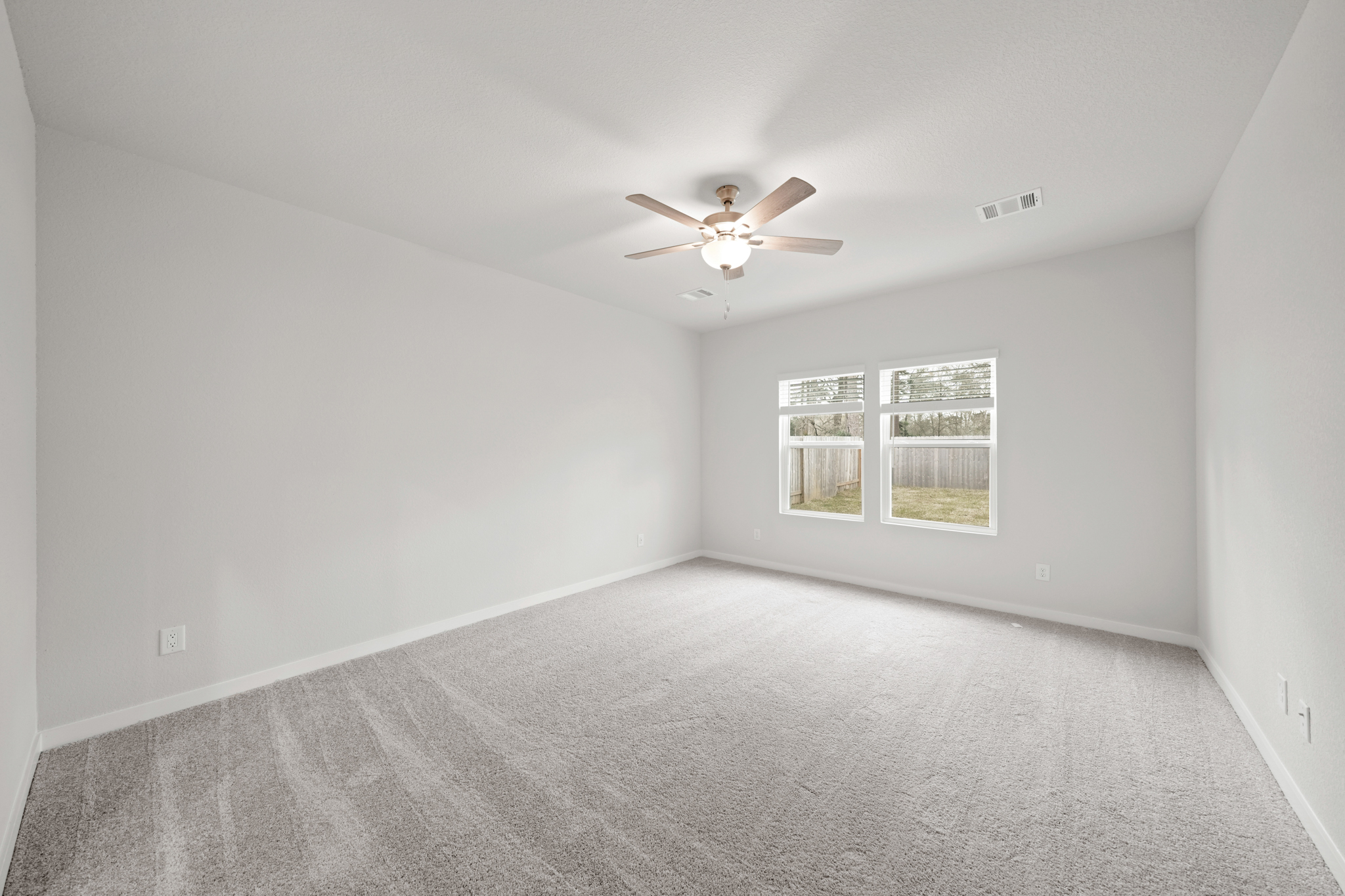 A room with a ceiling fan and a carpet.