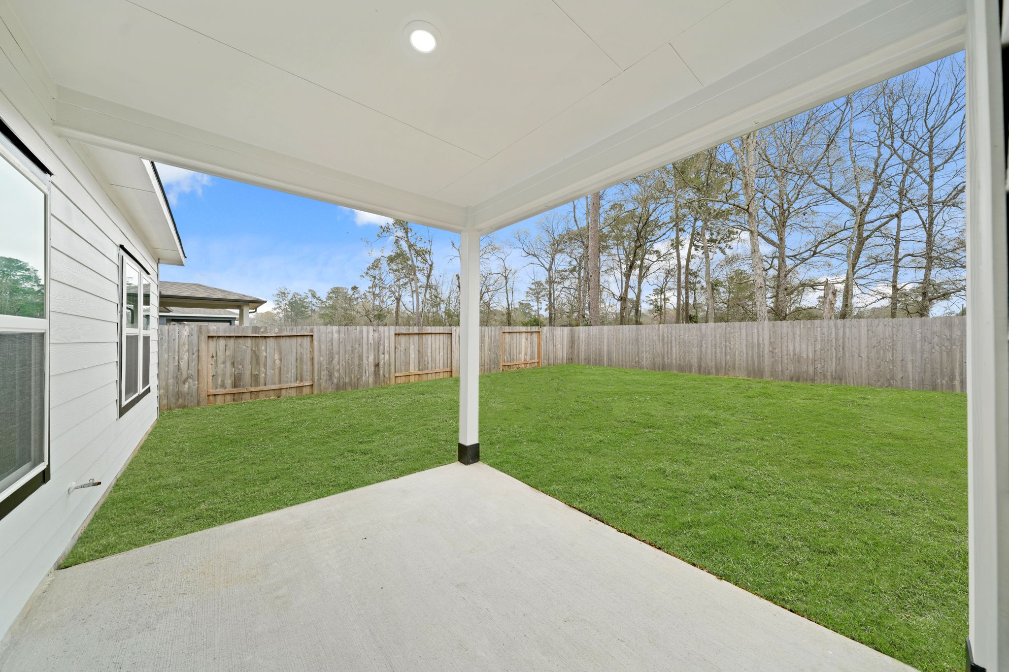 A backyard with a fence and a grass yard.