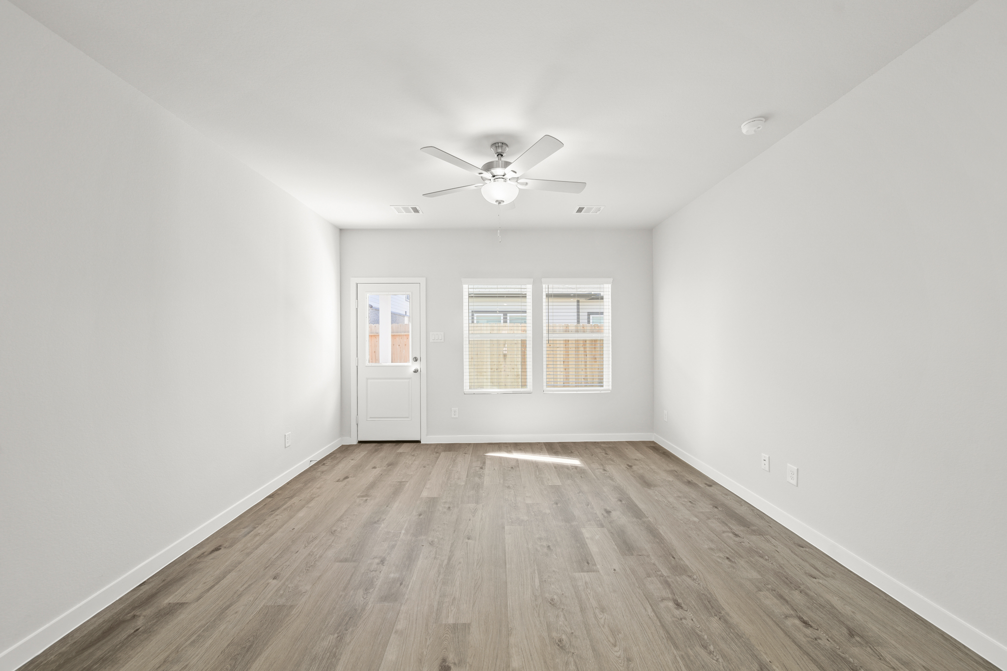 A room with a ceiling fan and a wood floor.