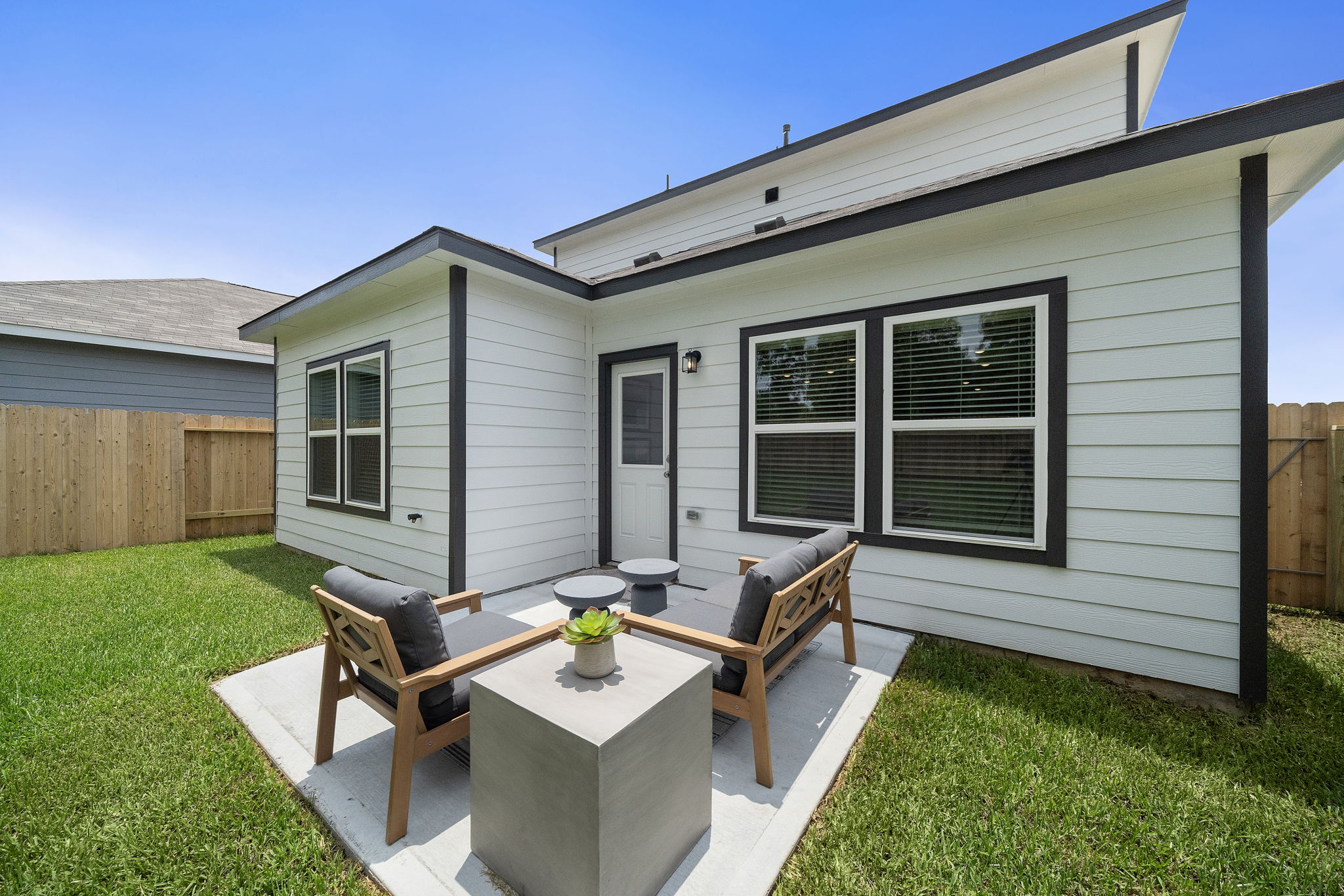 A backyard with a bench and a table and chairs.