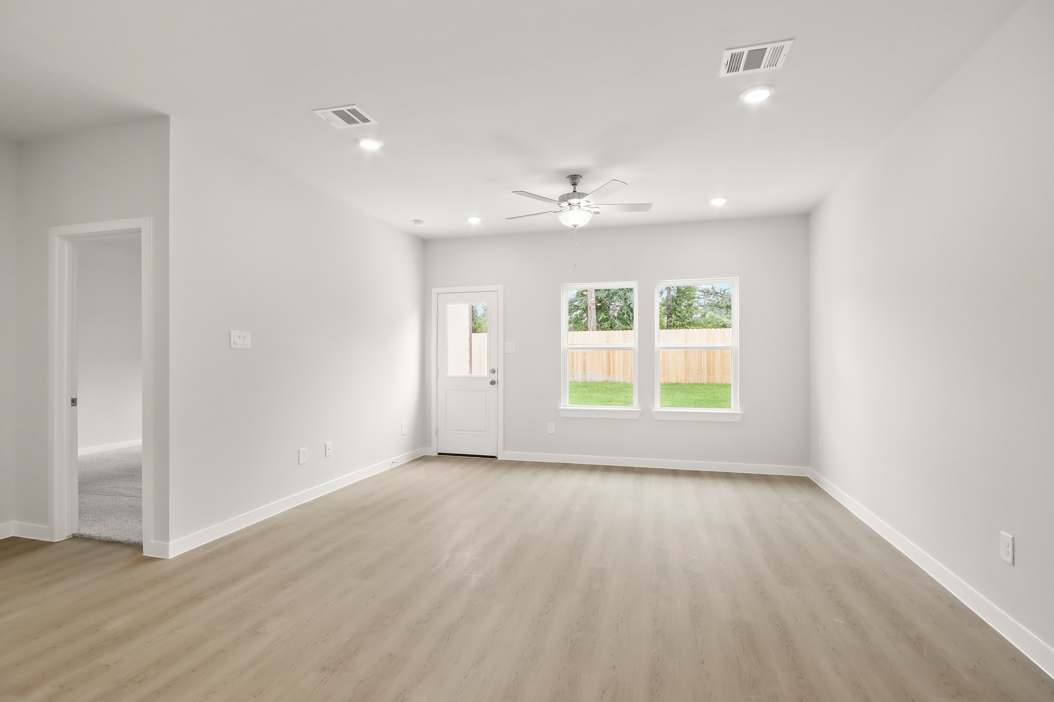 A room with a wood floor and a ceiling fan and a wood floor.