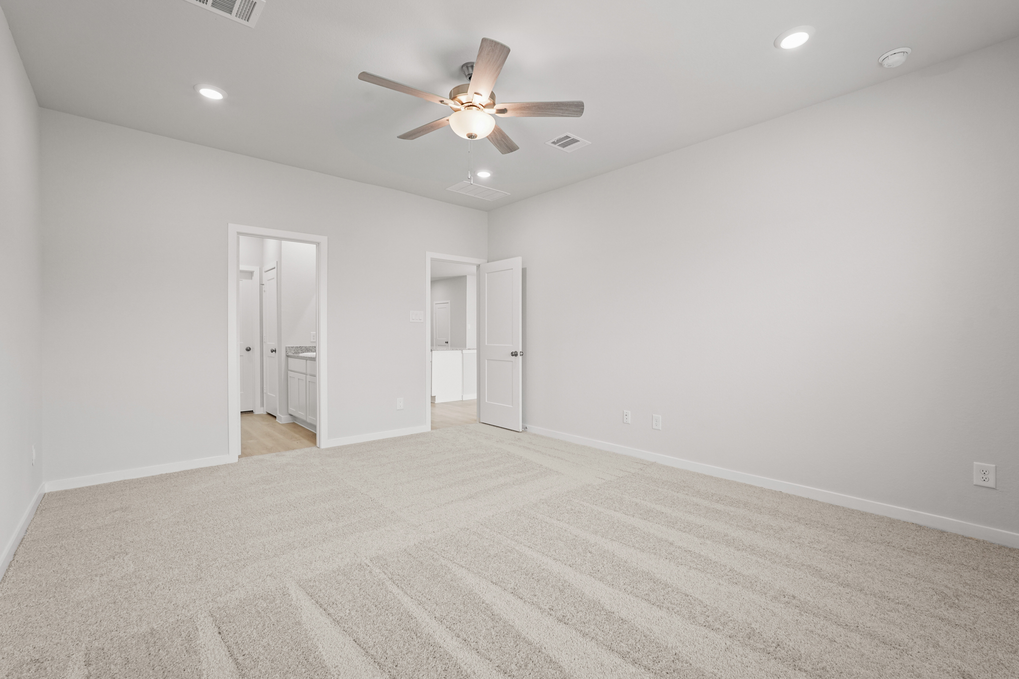 A room with a ceiling fan and white walls.