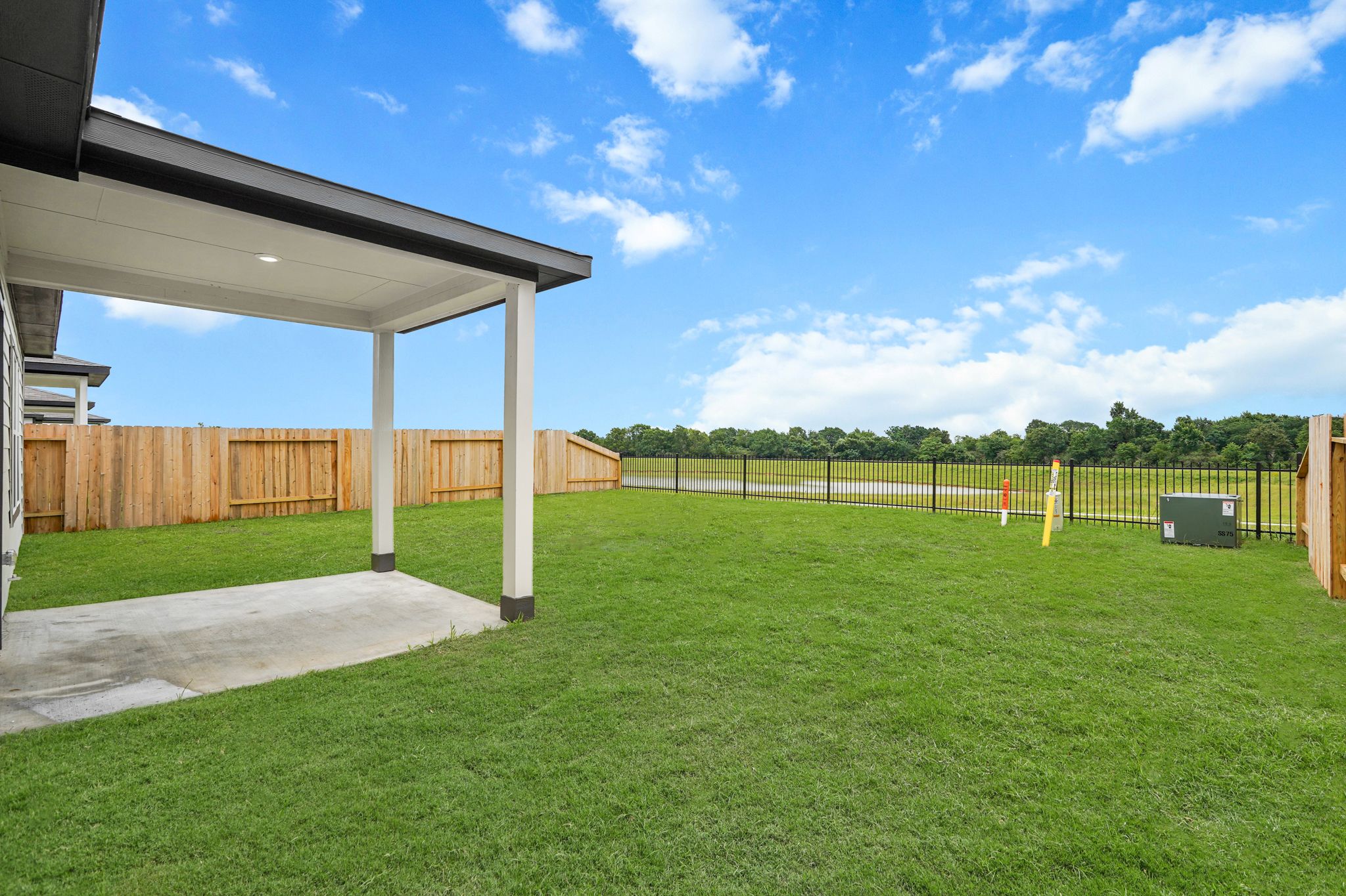 A grass yard with a fence and a building.