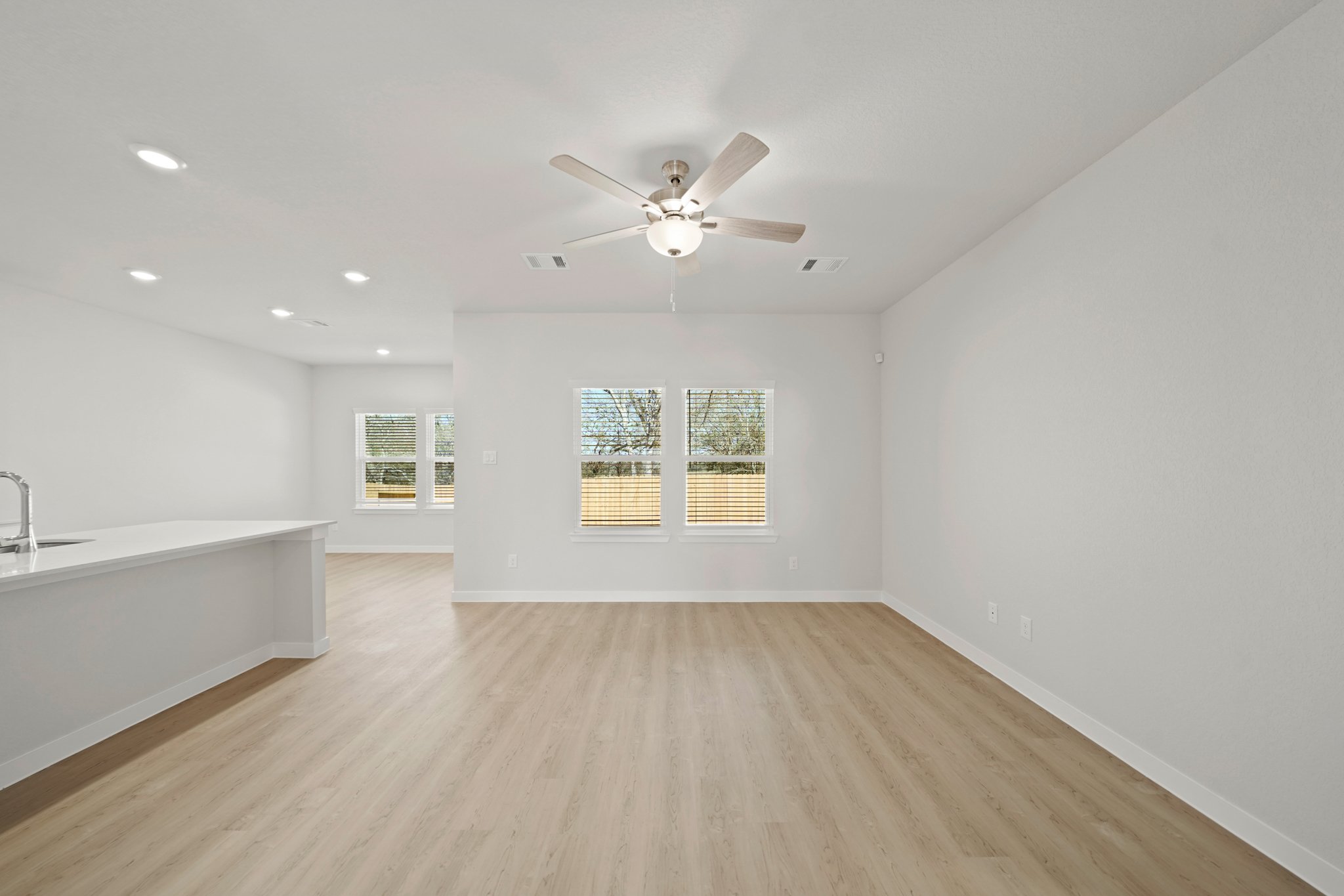 A large empty room with a ceiling fan and a wood floor.