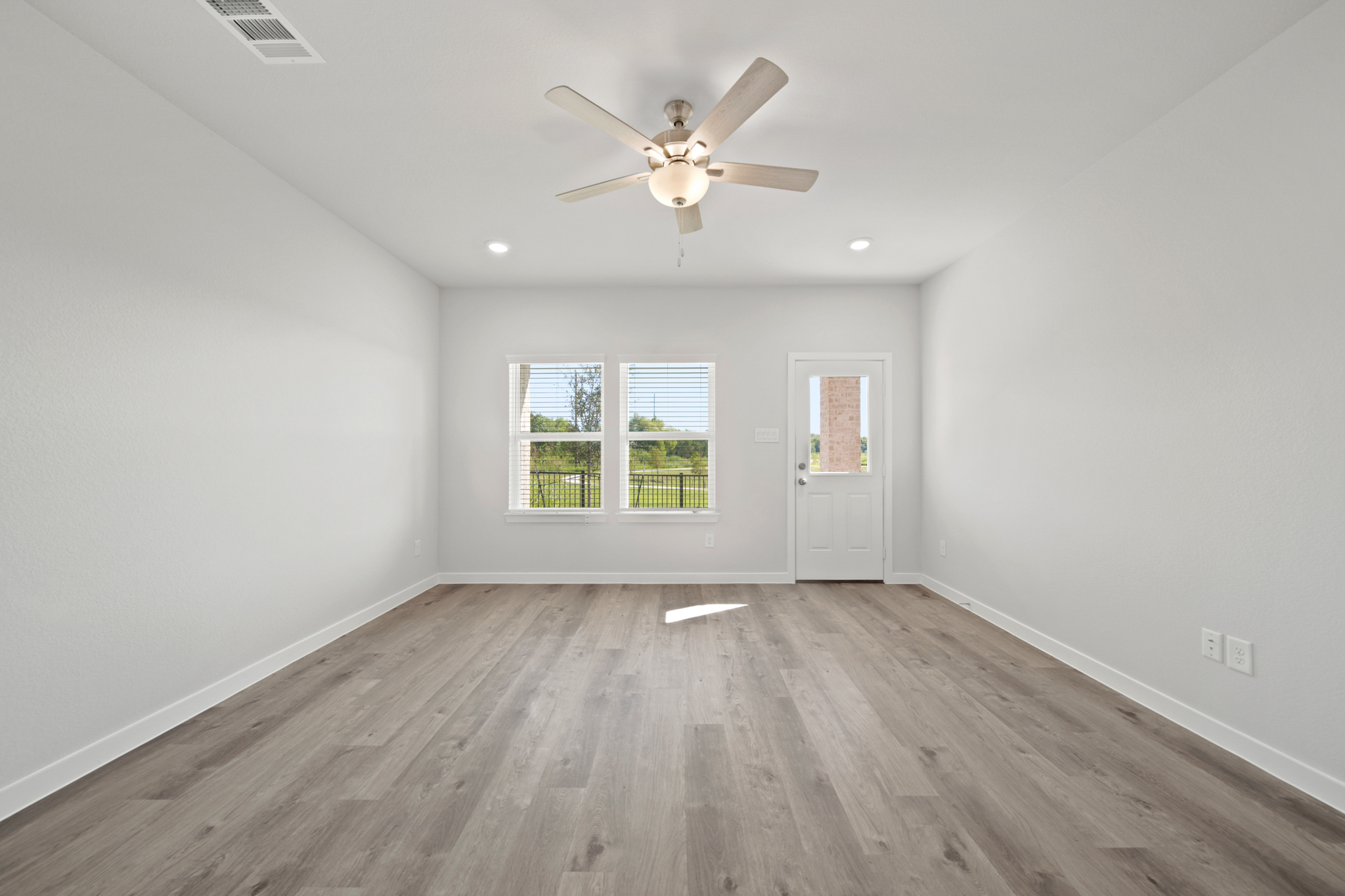 A room with a ceiling fan and a wood floor.