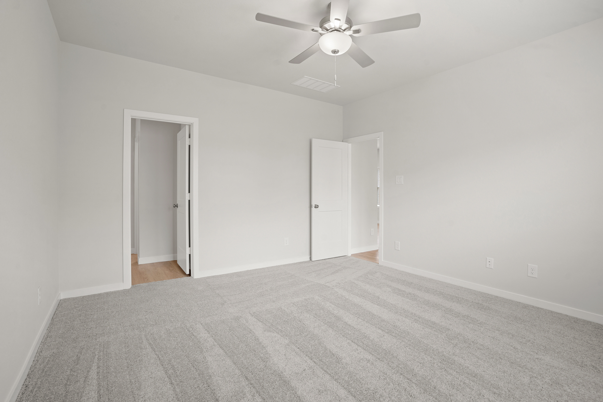 A room with a ceiling fan and a door.