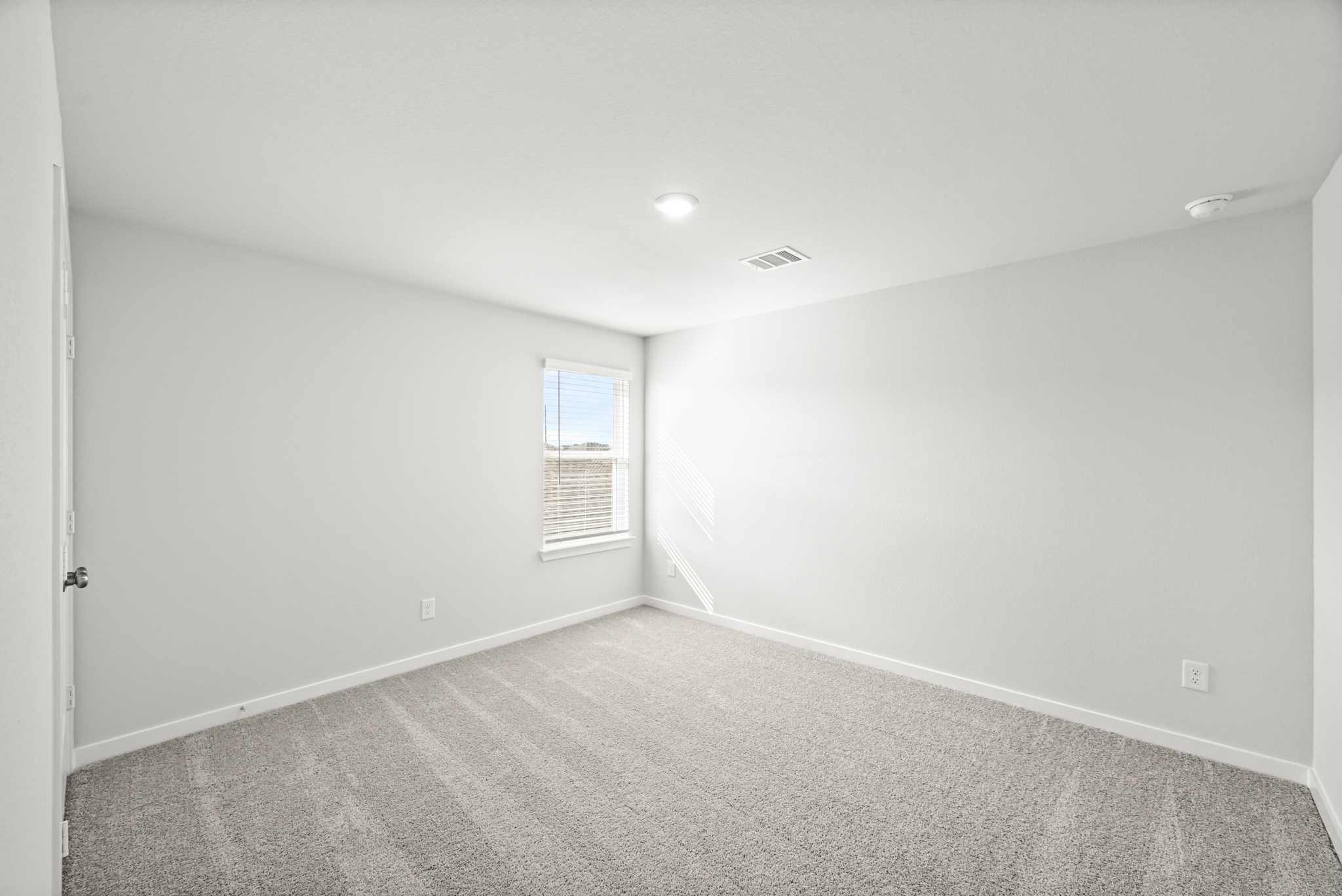 A room with a carpet and a window.