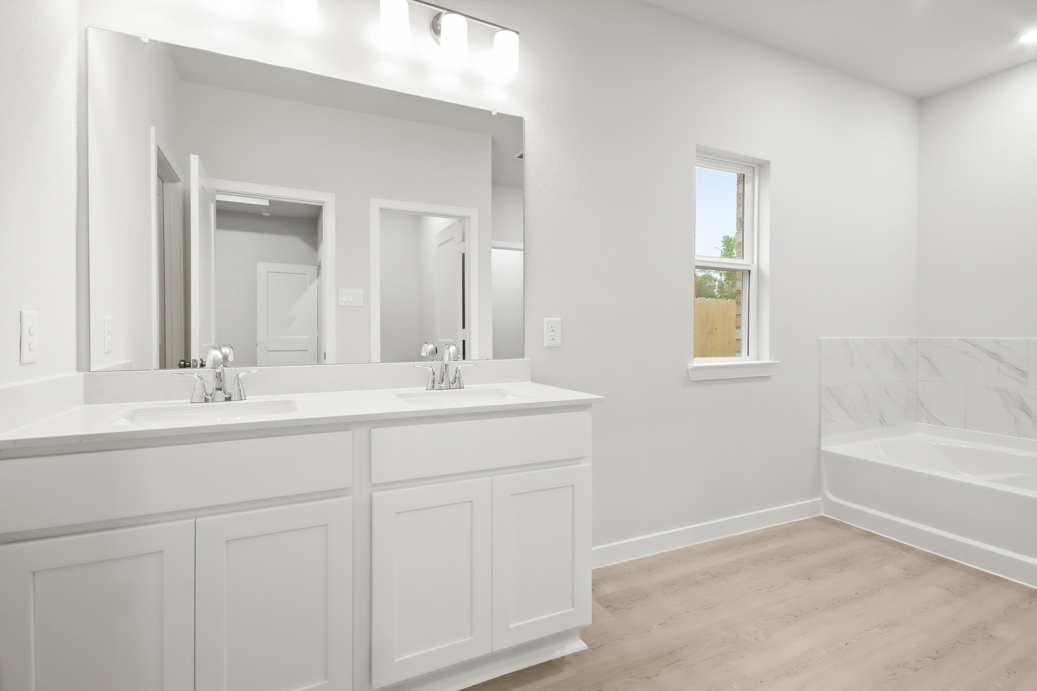 A bathroom with a tub sink and a mirror.