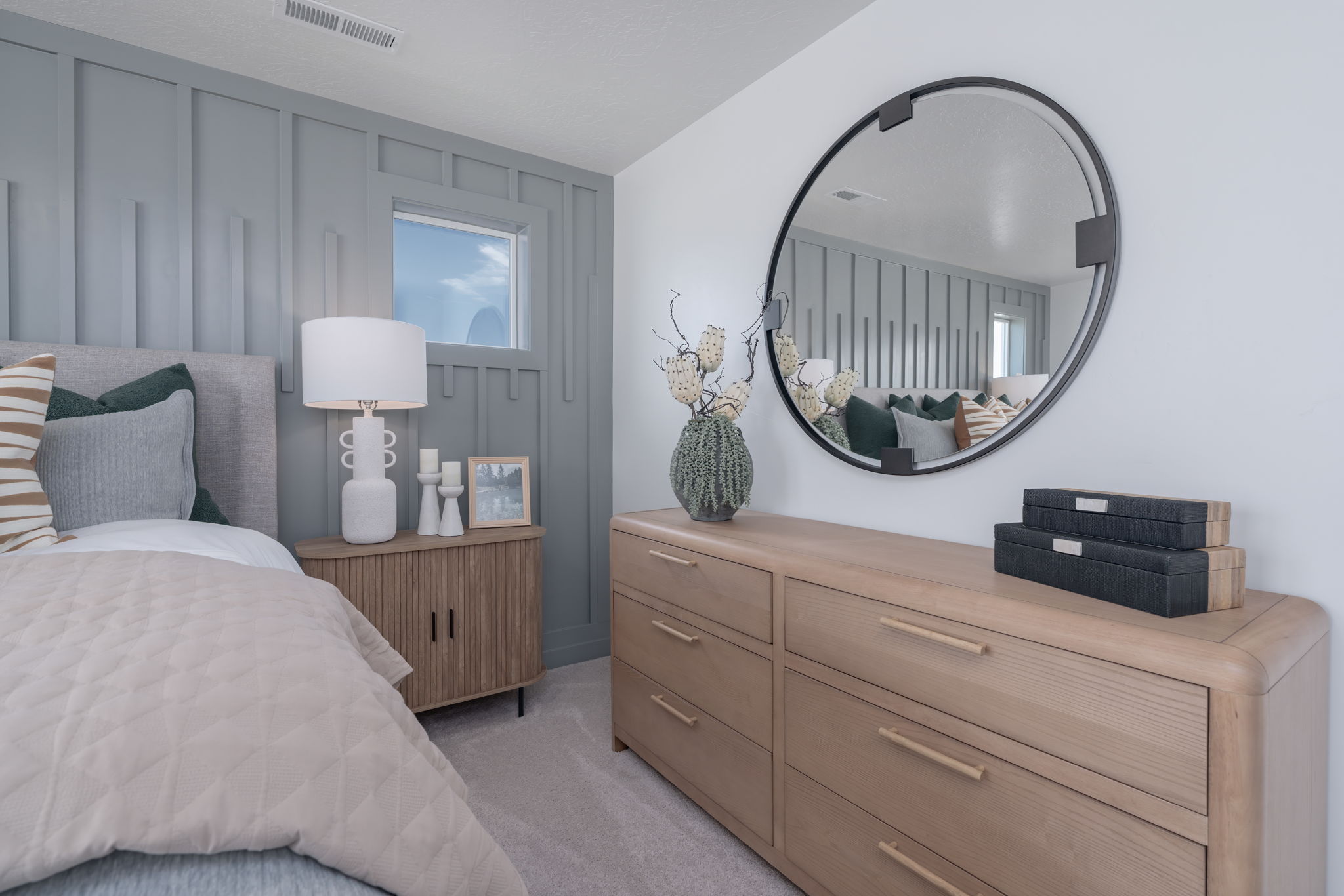 A bedroom with a mirror and a bed.