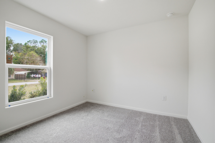 A room with a window and a carpet.