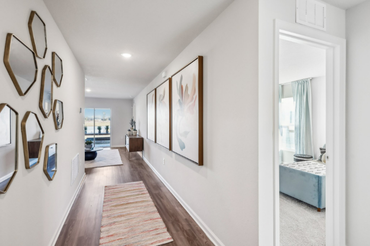 A hallway with a rug and a mirror.